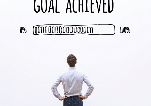 Image is of the back of a man in professional attire with the title 'Goal Achieved' above him with a bar graph showing his goal setting achievement.